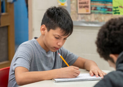 A child at a desk writing in a notebook.