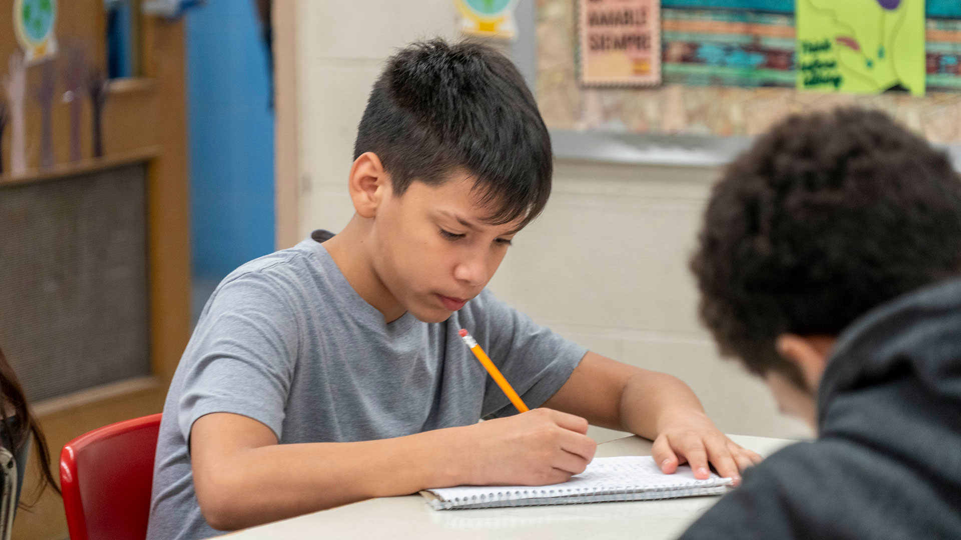 A child at a desk writing in a notebook.