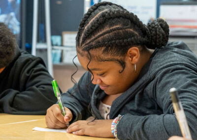 A girl at a desk writing on piece of paper.