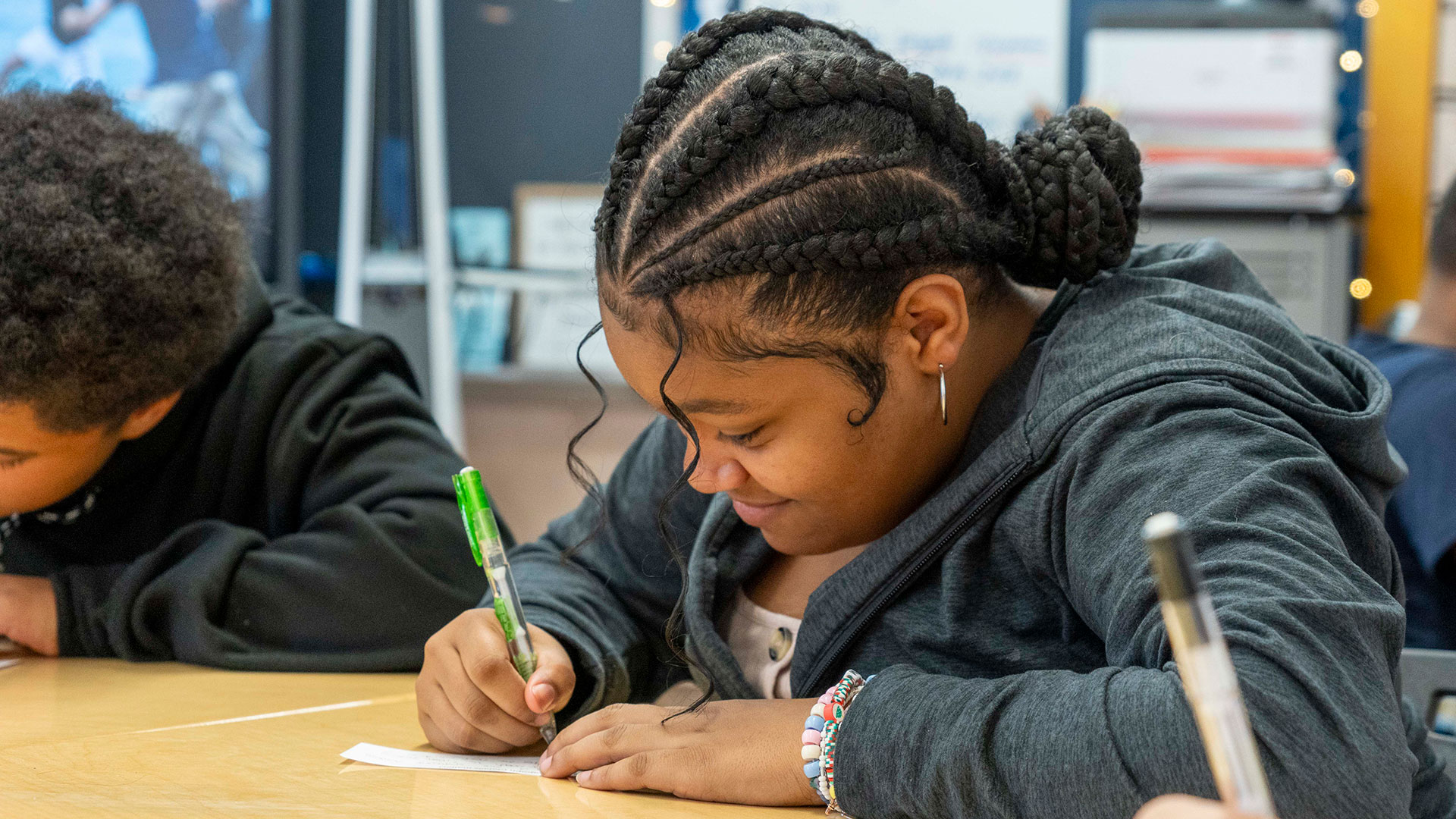 A girl at a desk writing on piece of paper.
