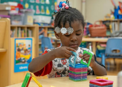 A young child stacking magnetic tiles.