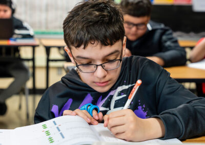 A student in a classroom writing in a workbook.