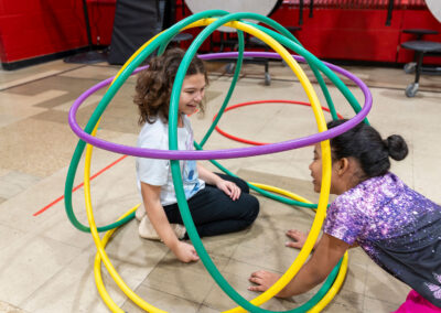 Two girls play in a tangle of hula hoops made to look like a sphere.