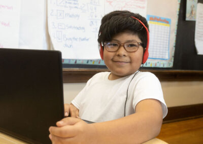 A boy with headphones using a computer.